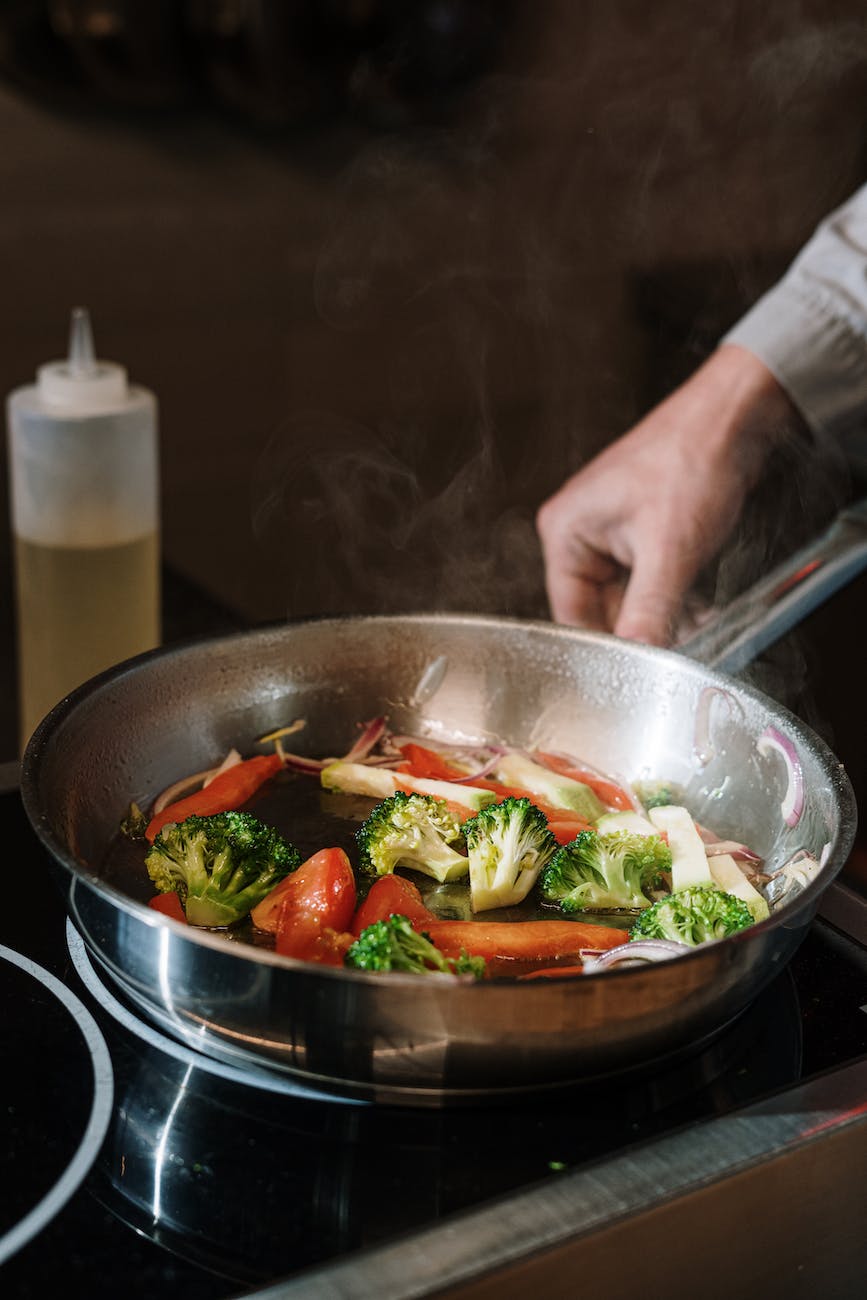 person holding black cooking pan with vegetable salad